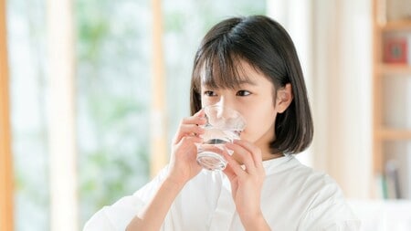 コップで水を飲んでいる女性