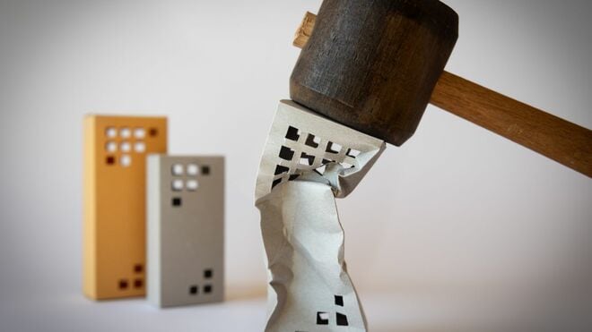 ハンマーで押しつぶされる不動産を模した紙の模型