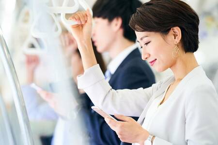 電車でスマホをチェックする女性