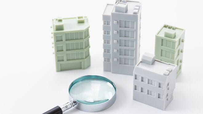 複数のビルの模型と虫眼鏡
