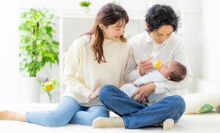 赤ちゃんにミルクを飲ましている夫婦